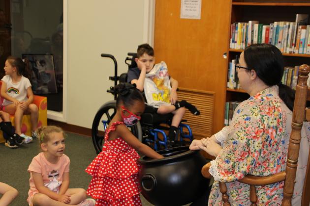 Arlee-Ana Rose Chevis, 3, receives a prize from a large plastic gumbo pot from Children’s Librarian Judy Kittles Wednesday.