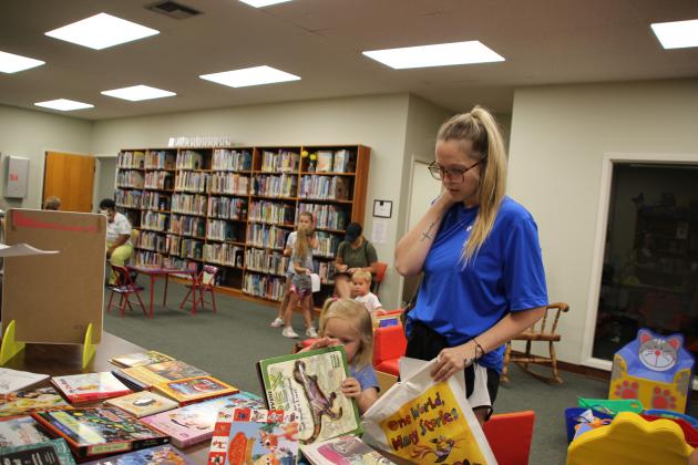 Greta Cormier, 3, and her mother McKenzie Cormier are looking through books to make a decision on receiving a free book during the library’s registration party held Monday.