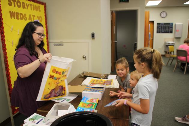 The McGee children, Olivia, John Thomas and Mary Katherine, are at the registration table Monday for the library’s Summer Reading program, themed “Allons Lire,” Cajun French for “Let’s Go Read.” Judy Kittles, children’s librarian, is assisting the children.