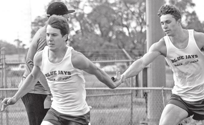 St. Edmund’s Luke Trahan takes the baton from Easten Coleman. (Photo by Tom Dodge)