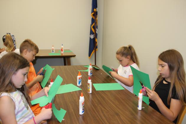 Older children enjoy crafting a gecko at the library.