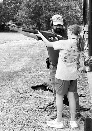Instructor teaching girl how to properly operate a shotgun