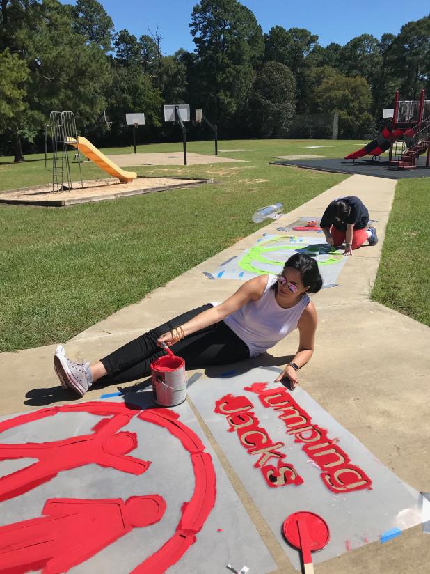 Volunteers paint exercise stencils next to the playground at Ruston Elementary. LSU AgCenter file photo by Cathy Judd.