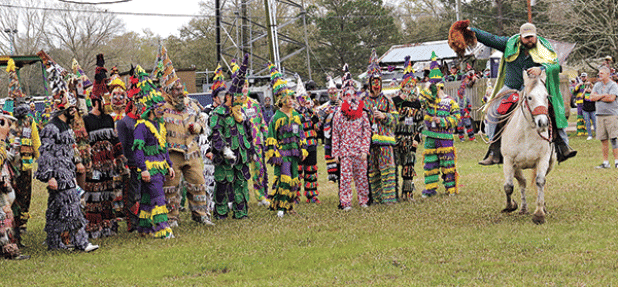 A capitaine holds a chicken aloft as runners are about to give chase in Le Vieux Mardi Gras De Cajuns de Eunice in 2023. (Photo by Harlan Kirgan)