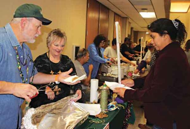 A Taster’s Choice ticket attendee Jalynn Cotton is wanting to try boudin at T-Boy’s booth in which Eric Soileau serves her a piece and watching on is Cathy Soileau. 