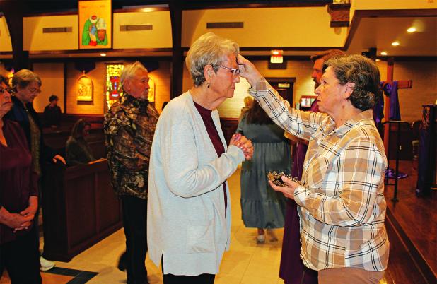 Mona Siebert, gives ashes to Gerrie Cormier, and the Rev. Sam Fontana is in the background. (Photo by Myra Miller)