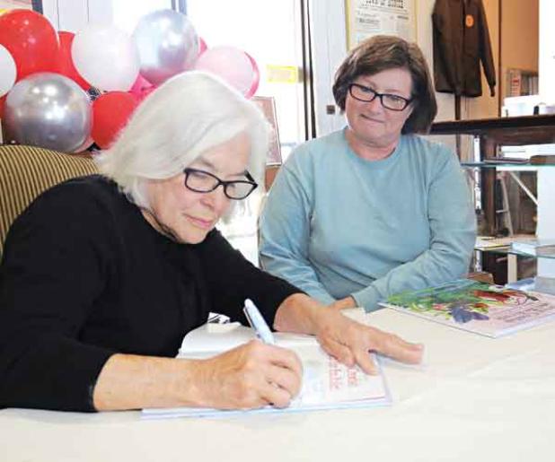 Julie Landry, daughter of author Mary Alice Fontenot, signs a copy of the 60th anniversary edition of “Clovis Crawfish and His Friends” for Debbie Charlie, of Ville Platte, on Saturday at a 61st birthday celebration for Clovis Crawfish. Landry has continued the series started by her mother from 18 books to 20. (Photos by Harlan Kirgan)