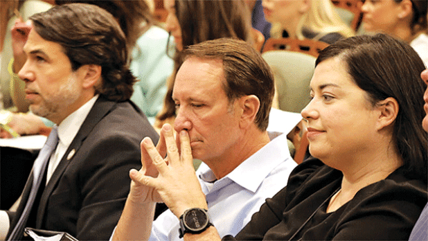 Gov. Jeff Landry, flanked by Deputy Chief of Staff Lance Maxwell and Executive Counsel Angelique Freel, waits to testify at the House Insurance Committee on April 16. (Photo by Wes Muller/Louisiana Illuminator)