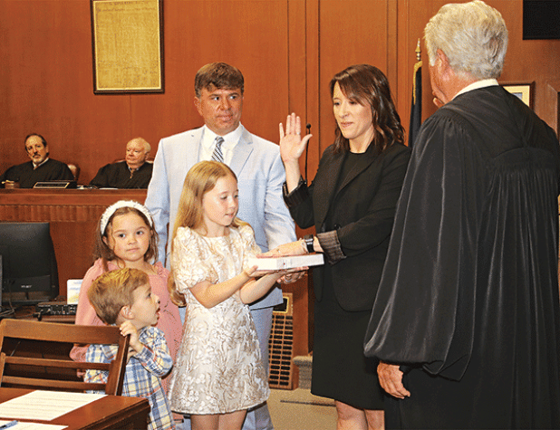 Laura Rougeau Garcille recites her oath of office delivered by State Supreme Court Judge James Genovese on Wednesday in the St. Landry Parish Courthouse. With her is her husband, Brett, and children, Emmy, 9, holding a Bible, Riley, 7, and John Roth, 4. Seated in the background are District Judges Gregory Doucet and James Dotherty. (Photos by Harlan Kirgan)
