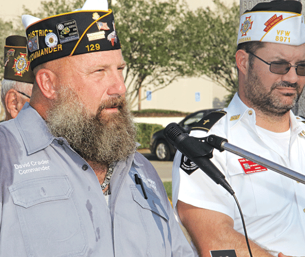 American Legion Post 129 Commander David Crader speaks at Monday’s ceremony.  At right is VFW Post  8971 member Paul Ganucheau. (Photo by Harlan Kirgan)