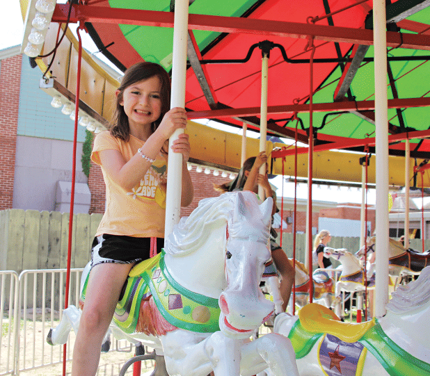 Hannah Miller rides on the carousel during last year’s St. Edmund Spring Fair. (Photo by Myra Miller)