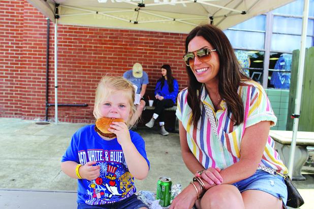 Lilly Moreau, 3, bites into a hamburger at the St. Edmund Spring Fair. She is with her Aunt April Murray. 