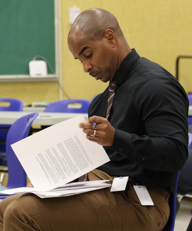 Milton Batiste, newly named St. Landry Parish school superintendent, goes over his contract at a special meeting on Tuesday. (Photo by Harlan Kirgan)