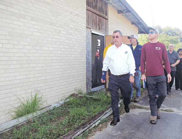 St. Landry Parish President Jessie Bellard, in the white shirt, leads a group on a walk around the vacant Moosa Memorial Hospital on Monday. He announced on Monday the building, vacant since 2006, will be demolished. At right in the red shirt is Phillip Cavins of Morgan and Morgan Land Preparation and Parish Council member Ernest Blanchard. (Photo by Harlan Kirgan)
