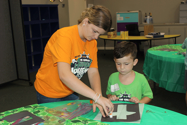 Marissa Stagg helps Gunner Ortego, 5, with a craft at Summer Surge held at New Hope Fellowship in Eunice. Kids enjoyed a summer camp this week with many fun activities, games, arts and crafts and more.