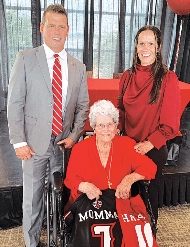 Deanna Habetz,  seated, was presented an official Ragin’ Cajun jersey and named “honorary coach” of the UL Lafayette team after her daughter, Alyson Habetz, right, was announced as the newest head coach. Making the presentations was Dr. Bryan Maggard, UL’s director of athletics. (Photo by Glenn Quebedeaux/Crowley Post-Signal)