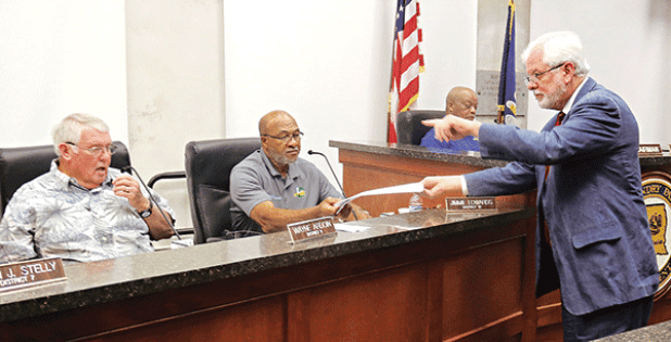 Gary McGoffin, right, an attorney representing the St. Landry Parish Council, hands out copies of a judgment to Parish Council members at a meeting Wednesday in Opelousas. Seated, from left, are Council members Wayne Ardoin, Jimmie Edwards and Jerry Red. The judgment is about a investigation by the Council into parish government employee terminations. (Photo by Harlan Kirgan)