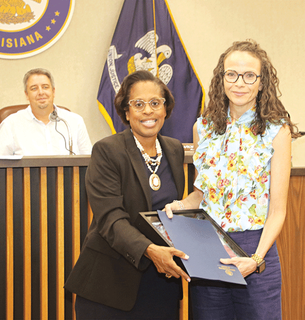 Eunice Alderwoman Germaine Simpson presents a flag and certificate to Paige Coutee in honor of Joseph “Joe” Coutee Jr. who operated Coutee’s Grocery. Looking on at left is Mayor Scott Fontenot. Turn to Page 10 for more photos from Tuesday’s city meeting. (Photo by Harlan Kirgan)