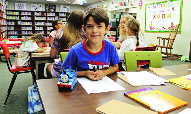 J.W. David, 7, begins to write his own story at the library Thursday morning during Imagination Camp.