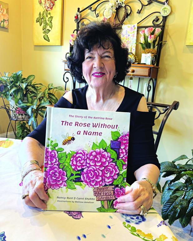 Peggy Martin holds the children’s book that tells the story of the rose that bears her name. (Photo by Tobie Blanchard/LSU AgCenter)
