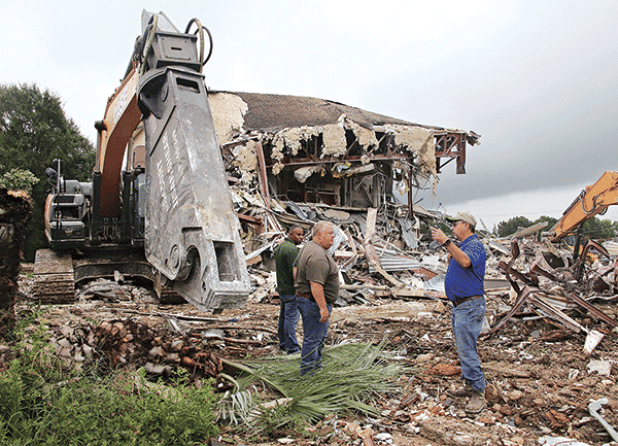 St. Landry Parish Government employees worked the weekend to demolish the second story of the old Moosa Memorial Hospital From left, are Eric Chisely, building maintenance supervisor; Jessie Bellard, parish president; and Todd Darbonne, fleet manager. They are by the shear tool used to cut through steel at the old hospital. (Photos by Harlan Kirgan) 