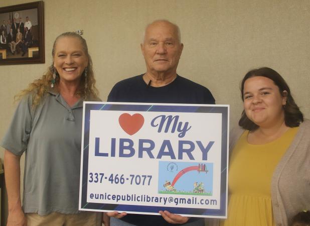 The Friends of the Eunice Public Library is selling yard signs promoting the library for $15 each. The signs, which were introduced at Tuesday’s Eunice city council meeting,  are available at the library. Holding a yard sign are, from left, Jena Donaldson, children’s program librarian; Tony Baltakis, president of the Library Board of Control; and Allison Duplechain, librarian. (Photo by Harlan Kirgan)