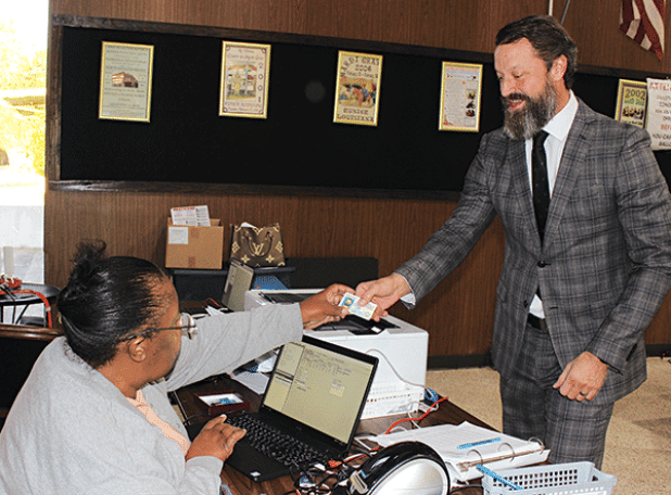 Caleb Aguillard hands his ID to Cynthia Martin as he votes at Eunice City Hall on Wednesday. (Photo by Myra Miller) 