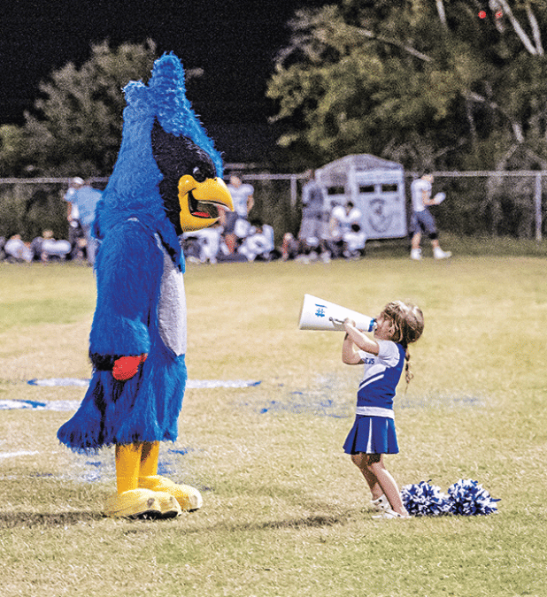 Karter Lejeune, 4,  uses a megaphone to chat with St. Edmund mascot Bluedreaux (Melody Fuselier) during last week’s game against Westminster Christian Academy. Karter’s parents are Dana and Jared Lejeune. Her brother, Jay, and sister, Caroline, are multi-sport athletes at St. Edmund. (Photo by Dwight Jodon)