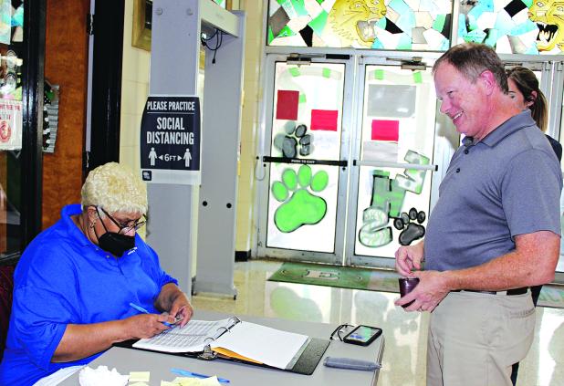 Debra Gallien, an election commissioner, views Dr. Jerome Fontenot’s driver’s license at a voting poll at Eunice High School Tuesday afternoon. (Photo by Myra Miller)