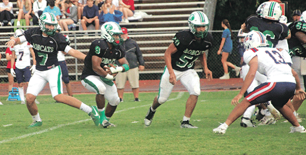The Eunice High Bobcats started off slow, but made adjustments and defeated the North Vermilion Patriots 14-6 in a jamboree contest on Aug. 29 in Rayne. From left, Montana Brown, quarterback,completes a handoff to running back Bryan Allen as guard Christopher Malbrough leads for a block. (Photo by Rhett Manuel)