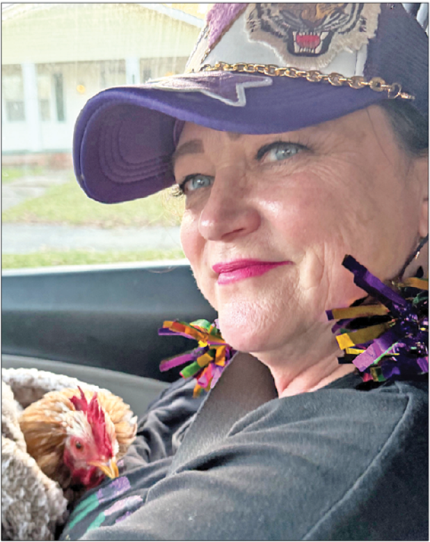 Audrey Houston, pictured, and her friend Stacy Parker, both of Baton Rouge, left the 2025 Cajun Mardi Gras Festival with a feathered souvenir — Eunice the rooster.  Houston holds Eunice on the drive back to Baton Rouge. (Submitted photo)