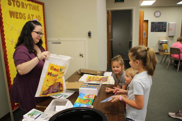 The McGee children, Olivia, John Thomas and Mary Katherine, are at the registration table Monday for the library’s Summer Reading program, themed “Allons Lire,” Cajun French for “Let’s Go Read.” Judy Kittles, children’s librarian, is assisting the children.