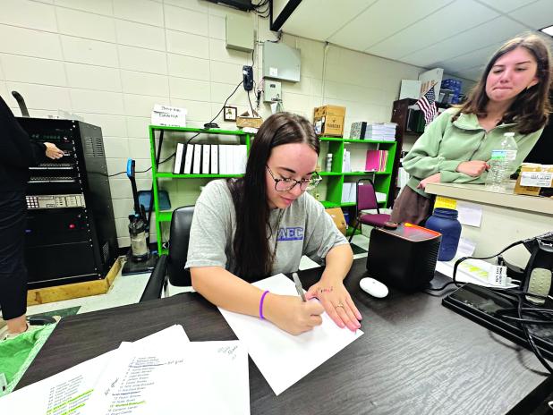 Lainey Fruge, 17, of Eunice High School, writes her name in cursive, while classmate Kelsie  Gaspard, 18, watches. Both students said they only know how to write their names in cursive. (Photo by Rebecca Chaisson) 