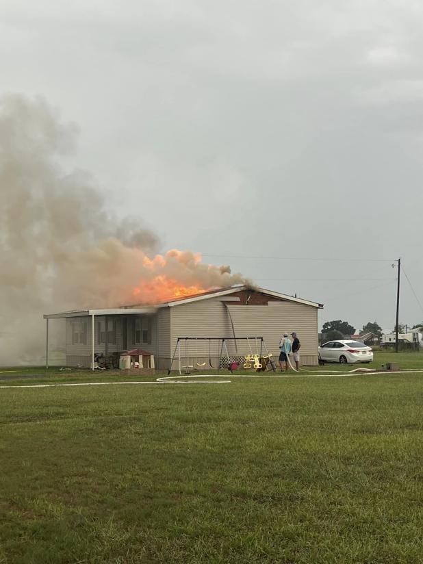 The home of Neal Leger and Janice Arnold on Pelican Loop near Basile was a complete loss as the result of a fire caused by a lightning strike. The fire is shown above in the roof before it overtook the entire home. (Submitted photo)