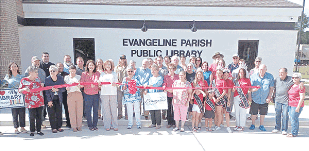 Local and parish library board members and employees, pastors, community leaders, library patrons, and Miss Basile royalty along with contractors who built the new Basile library branch building are gathered around Faye Langley, local representative on the Evangeline Library Board of Control, as she cuts the ceremonial ribbon at the library’s grand opening. 