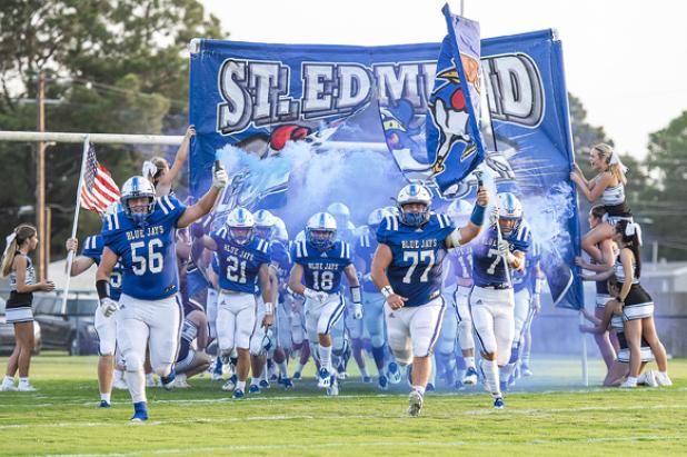 St. Edmund runs through its banner before the Oakdale game.
