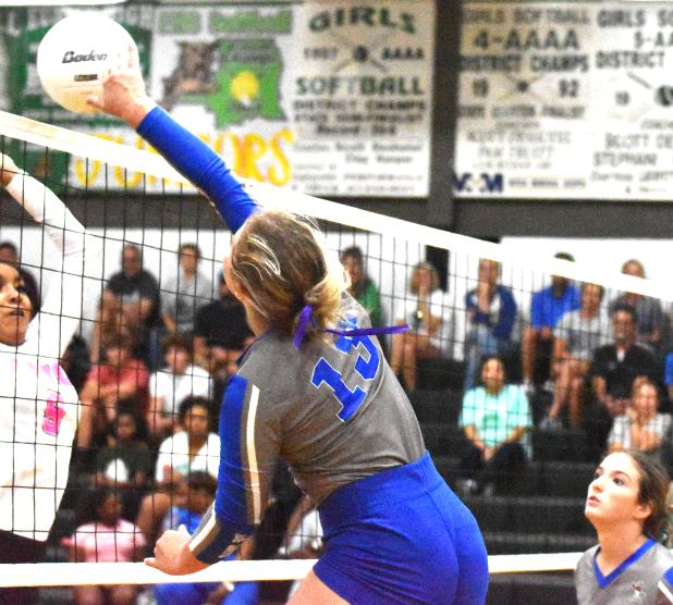 St. Edmund’s Ava Smith hits the ball as Eunice High’s Denina Ned defends on the play.