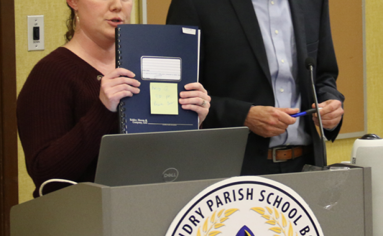 Tressa Miller, right, St. Landry Parish School Board finance director, holds an audit report up. At right is Casey Ardoin, CPA, of the Kolder, Slaven & Company. They were at the School Board’s Finance Committee meeting Monday in Opelousas. (Photo by Harlan Kirgan)