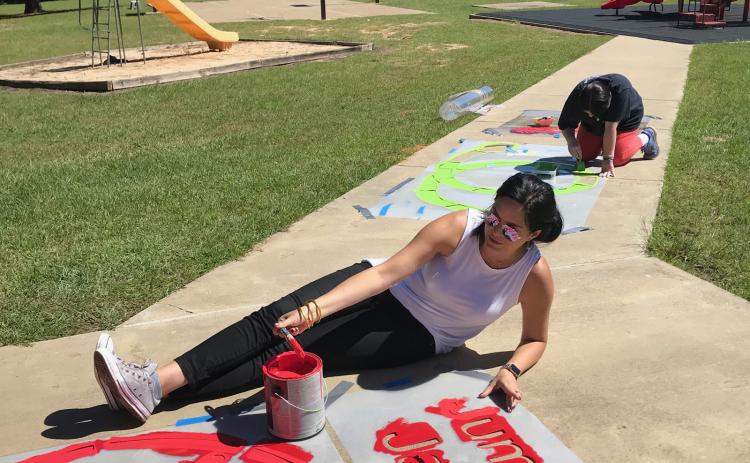 Volunteers paint exercise stencils next to the playground at Ruston Elementary. LSU AgCenter file photo by Cathy Judd.