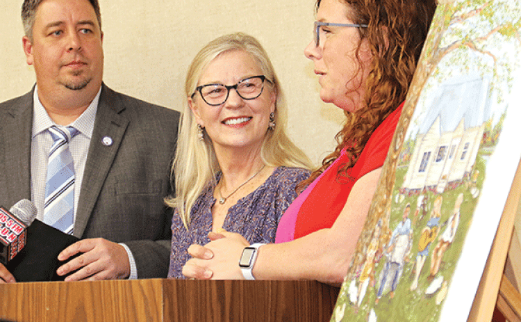 A painting by Eunice artist Amelia Vidrine was unveiled at the Eunice Board of Aldermen meeting on Feb. 14. The painting depicts the Dewey Balfa homestead is on a poster for the Dewey Balfa Cajun & Heritage Week set March 20 to 25 at Lakeview Park & Beach in Eunice. From left, are Mayor Scott Fontenot, Louisiana Folk Roots Director Jeanne Solis and Vidrine. (Photo by Harlan Kirgan)