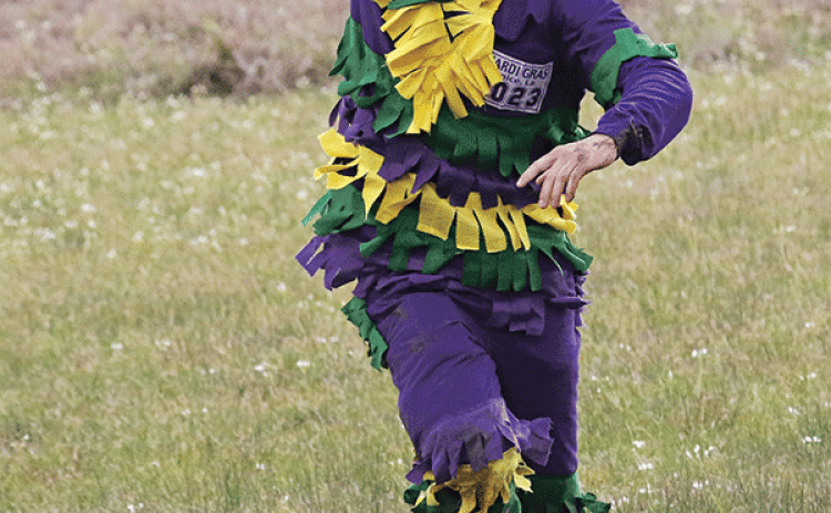 Hunter Aucoin holds a chicken aloft after catching it during the Eunice Mardi Gras Run. Aucoin was at the field at Parish Road 6-325 and North Bobcat Drive. (Photo by Harlan Kirgan)