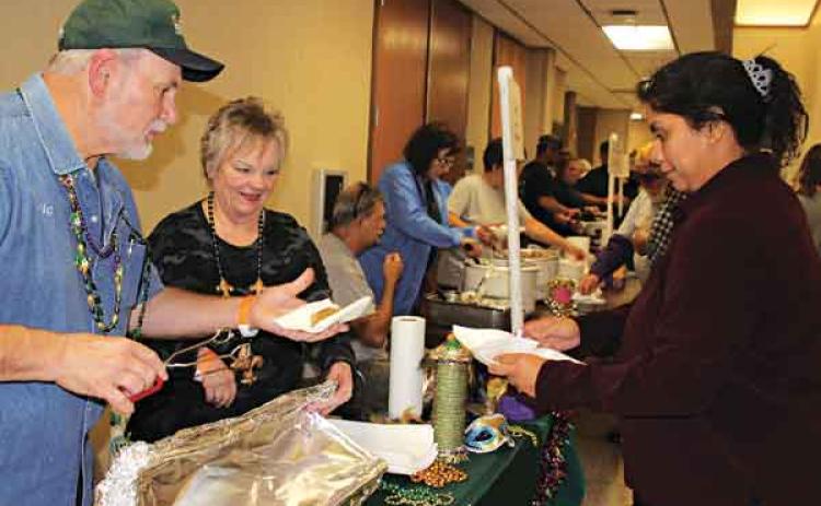 A Taster’s Choice ticket attendee Jalynn Cotton is wanting to try boudin at T-Boy’s booth in which Eric Soileau serves her a piece and watching on is Cathy Soileau.