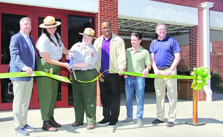 Cutting a ribbon marking the reopening of the Prairie Acadian Cultural Center on Friday were, from left, Scott Fontenot  Eunice mayor; Laura McDonald and Lainey Binnix, park rangers; Herman Fuselier, parish tourism director; Justin Lemoine, executive director of the Atchafalaya National Heritage Area; and Dwight Jodon, Eunice Rotary Club member. (Photo by Harlan Kirgan)