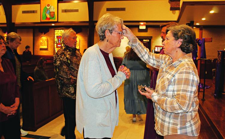 Mona Siebert, gives ashes to Gerrie Cormier, and the Rev. Sam Fontana is in the background. (Photo by Myra Miller)