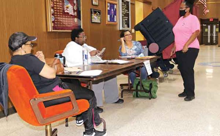 Voting was slow at the Eunice City Hall polling place. Stephanie Monte, standing right, was being redirected to vote at the Southeast Community Center at about 7:30 p.m. Saturday. Election workers, from left, are Theresa Guillory, Carla Frank and Sandra Wikins. (Photo by Harlan Kirgan)