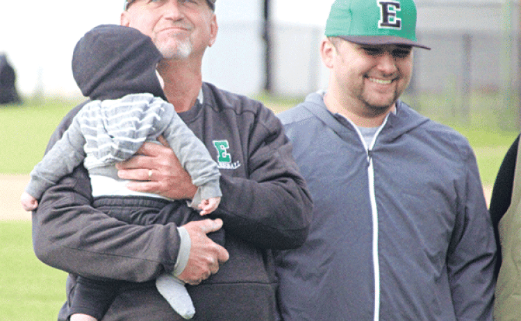 Eunice High head coach Scott Phillips is holding his grandson, Tommy, during Scott Phillips Day prior to Eunice’s game against Oakdale on Monday. In 33 seasons as a head coach, 31 at Eunice High, Phillips has accumulated nearly 700 wins. He’s also recorded 31-straight playoff appearances, 22 seasons of 20 or more wins and 15 district championships in a decorated career. At right is his son, Austin, (Photo by Rhett Manuel)