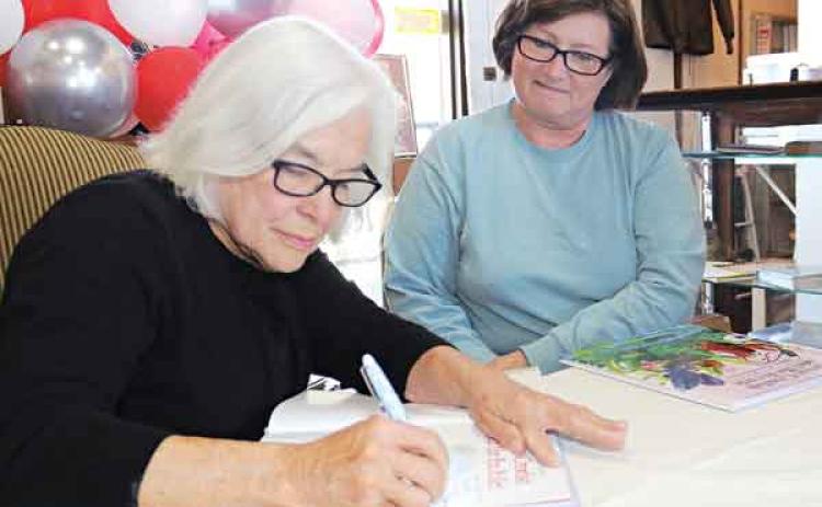 Julie Landry, daughter of author Mary Alice Fontenot, signs a copy of the 60th anniversary edition of “Clovis Crawfish and His Friends” for Debbie Charlie, of Ville Platte, on Saturday at a 61st birthday celebration for Clovis Crawfish. Landry has continued the series started by her mother from 18 books to 20. (Photos by Harlan Kirgan)