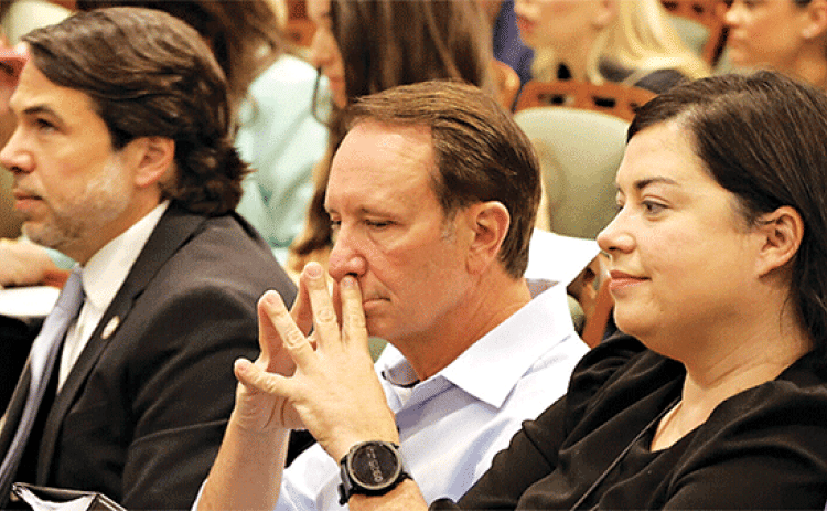 Gov. Jeff Landry, flanked by Deputy Chief of Staff Lance Maxwell and Executive Counsel Angelique Freel, waits to testify at the House Insurance Committee on April 16. (Photo by Wes Muller/Louisiana Illuminator)
