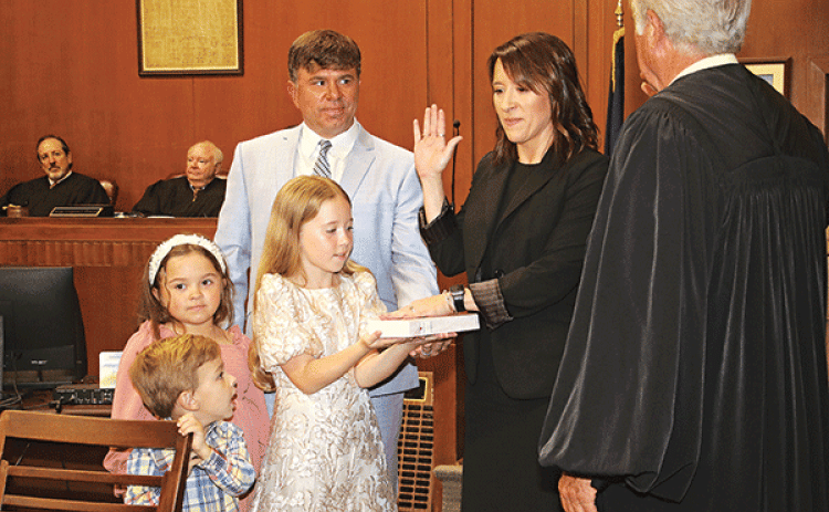 Laura Rougeau Garcille recites her oath of office delivered by State Supreme Court Judge James Genovese on Wednesday in the St. Landry Parish Courthouse. With her is her husband, Brett, and children, Emmy, 9, holding a Bible, Riley, 7, and John Roth, 4. Seated in the background are District Judges Gregory Doucet and James Dotherty. (Photos by Harlan Kirgan)