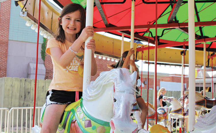 Hannah Miller rides on the carousel during last year’s St. Edmund Spring Fair. (Photo by Myra Miller)